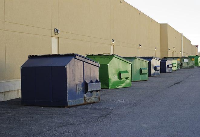 a forklift lifts a full dumpster from a work area in Ada, OH